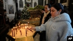 Suriyeli Hristiyan bir kadın, Esat'ın devrilmesinden sonraki ilk Pazar ayini sırasında Eski Şam'daki Mariamiya Ortodoks Kilisesi'nde mum yakıyor- 15 Aralık 2024.