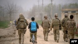 29 Mart 2012 - Afganistan'ın Kunduz vilayetinde sırtında Unicef çantasıyla bisikletine binen bir Afgan çocuk, bölgede görev yapan Alman askerlerinin arasından ilerliyor.